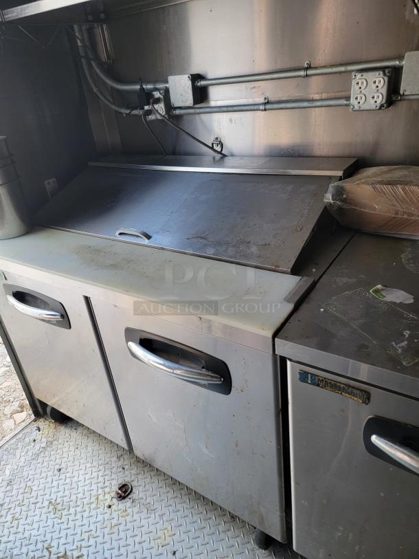 2021 Diamond Cargo mobile kitchen interior, featuring industrial-grade stainless steel surfaces, electric outlets, and storage units.