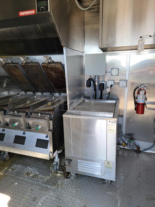 2021 Rock Solid Cargo mobile kitchen interior with CaptiveAire ventilation hood, fryers, stainless steel surfaces, and sanitation station.