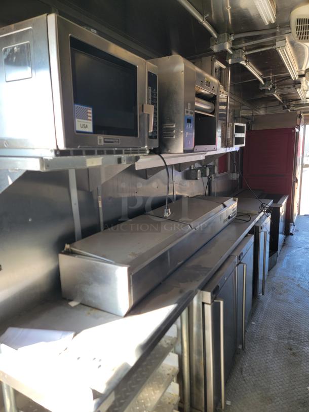 2021 Rock Solid Cargo 28' mobile kitchen, equipped with commercial appliances, ventilation hood, and stainless steel surfaces.