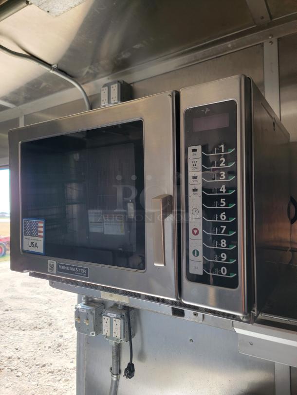 Commercial Menumaster microwave in a 2021 Rock Solid Cargo mobile kitchen. Features keypad, power outlets, and USA label.