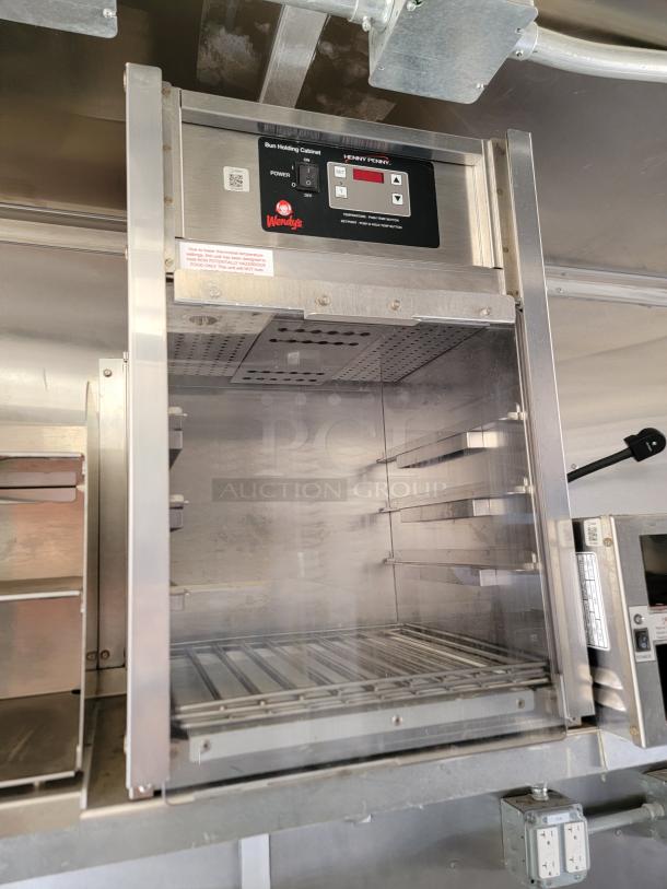 Henny Penny bun holding cabinet with digital controls and temperature display in mobile kitchen. Stainless steel construction.