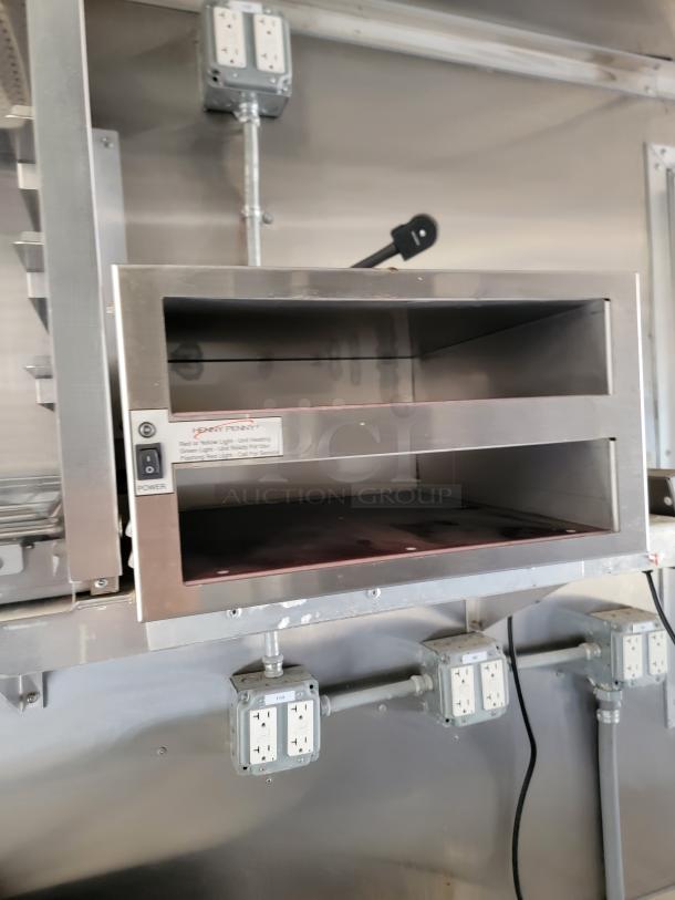 Industrial oven with stainless steel finish inside 2021 Rock Solid Cargo mobile kitchen, featuring power indicator and multiple outlets.