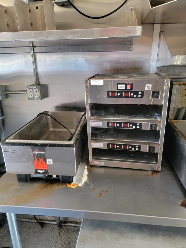 2021 Rock Solid Cargo mobile kitchen with Cayenne warmer, commercial oven stack, stainless steel surfaces, and visible signs of use.