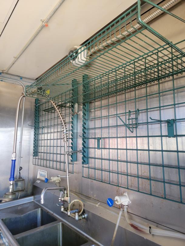 28' Diamond Cargo food trailer interior with stainless steel sinks, overhead wire racks, and plumbing fixtures for high-capacity use.