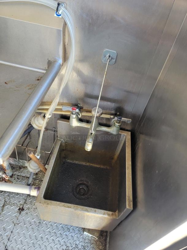 Stainless steel sink in a 2020 Diamond Cargo 28' food trailer, featuring plumbing fixtures and durable diamond plate flooring.