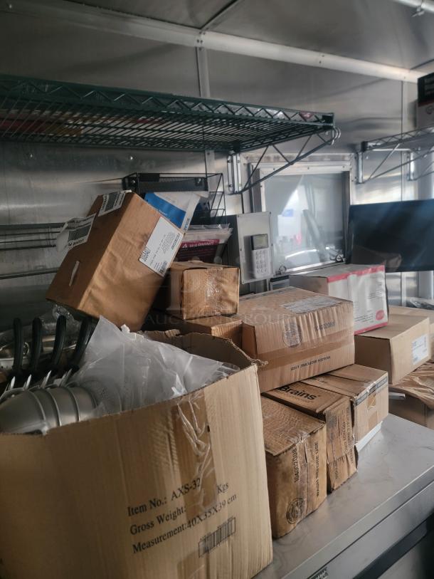 2021 Rock Solid Cargo 8.5' x 24' food trailer interior with shelving, cardboard boxes, and kitchen equipment.