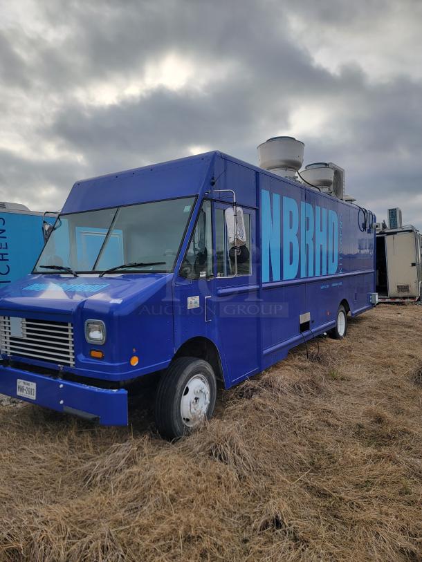 Blue food truck labeled "NBRHD Kitchens," parked on grassy field, featuring ventilation units, in good condition.