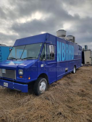 Blue food truck labeled "NBRHD Kitchens," parked on grassy field, featuring ventilation units, in good condition.