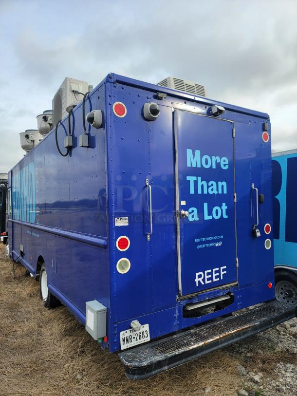 Blue food truck with "More Than a Lot" and REEF branding, side vents, rear door, and Texas license plate.