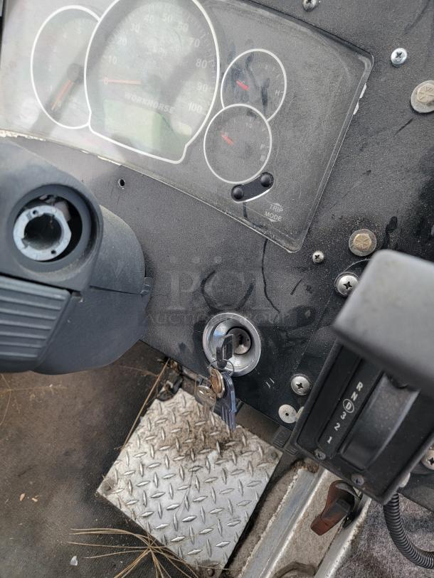 Instrument panel with speedometer marked "Workhorse," key in ignition, diamond plate floor, gear shift showing "R N 3 2 1."