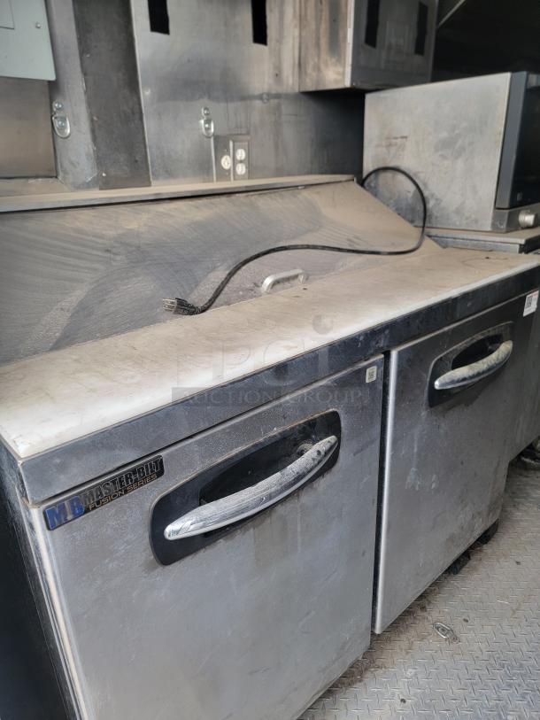 Master-Bilt Fusion Series refrigerated prep table with dual storage compartments, stainless steel, visibly dusty condition.