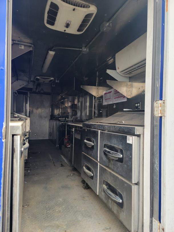 Interior view of a mobile kitchen unit with stainless steel appliances, storage drawers, and air conditioning units. Good condition.