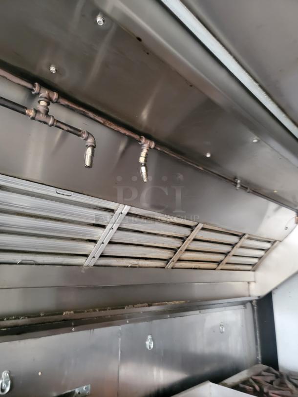 Industrial-grade stainless steel vent hood with exposed piping, featuring a foldable slatted design. Used condition.