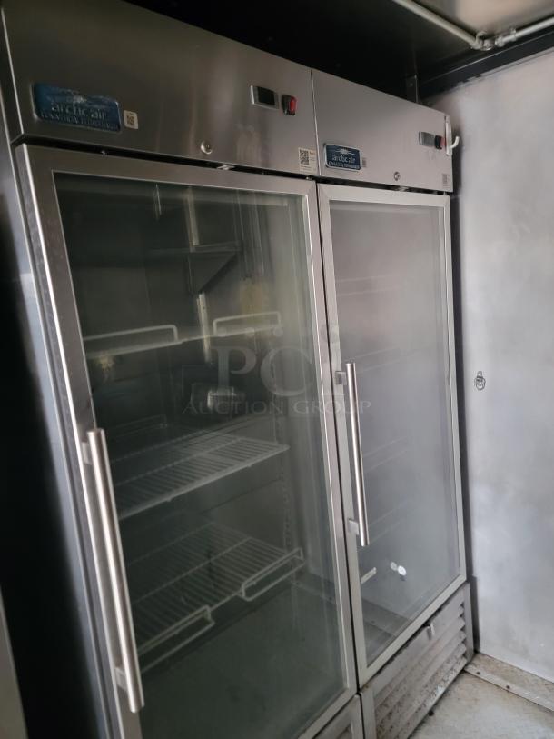 Arctic Air commercial double-door refrigerator with glass fronts, stainless steel exterior, adjustable shelves, and control panel.