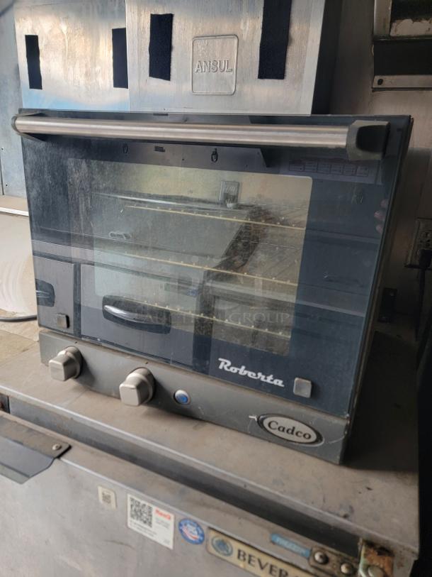 Cadco Roberta commercial oven with glass door and dual knobs, used condition, visible brand logo, industrial setting.