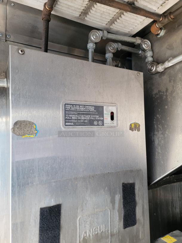 Ansul R-102 wet chemical fire suppression system in stainless steel casing. Visible labels indicate system details. Good condition.