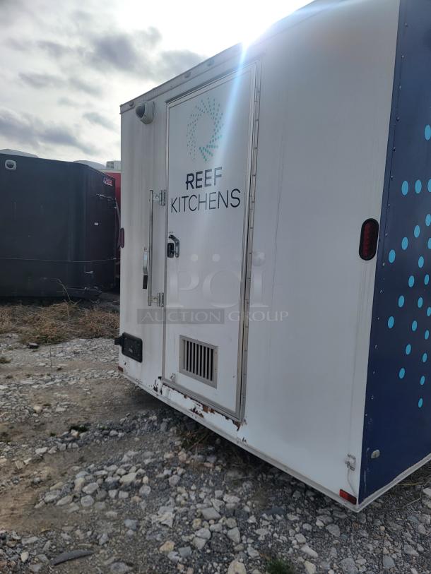 Mobile kitchen trailer by Reef Kitchens, white exterior with logo. Visible wear and rust. Suitable for food business operations.