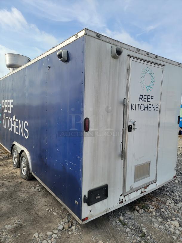 Mobile kitchen trailer with "Reef Kitchens" branding. Features exterior vents, dual axles, and security cameras. Worn condition.