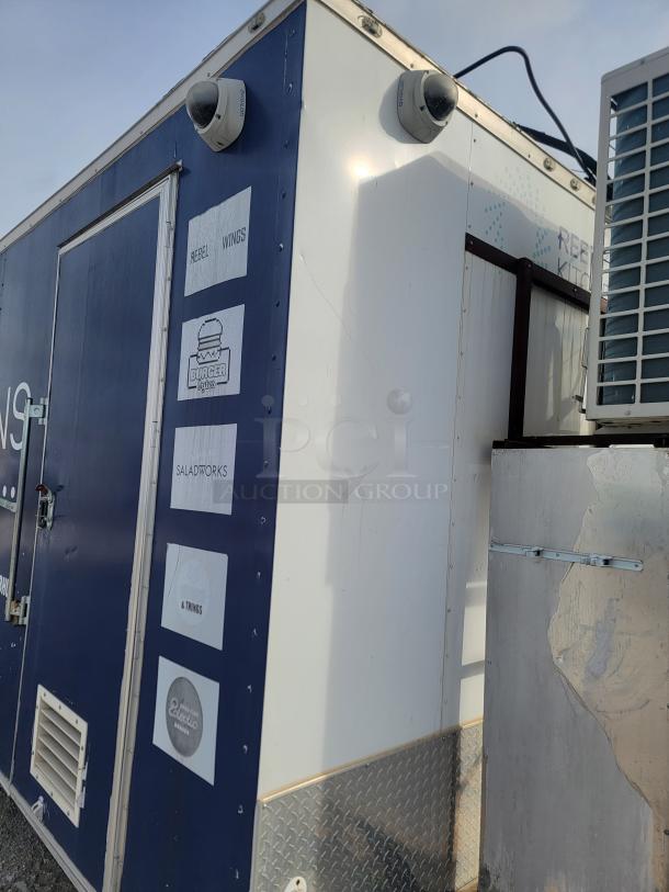 Mobile food trailer with branding logos, security cameras, and a metal exterior. Detailed labels include "Rebel Wings" and "Burger Bytes."