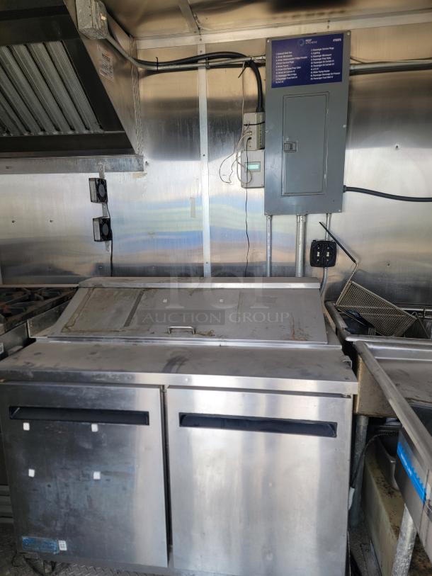 Commercial stainless steel refrigerator with double doors and top compartment. Shows wear, suitable for a kitchen setup.