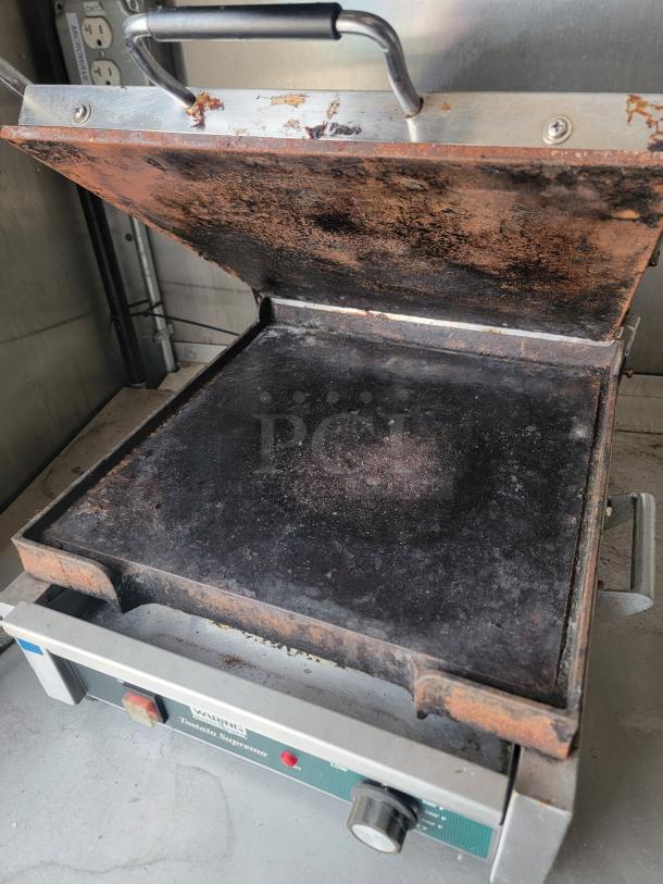 Waring panini press with visible rust and wear, model "Toasted Supremo," used condition.