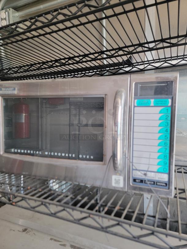 Stainless steel Sharp commercial microwave oven on metal rack, keypad with multiple settings, and clear display window.