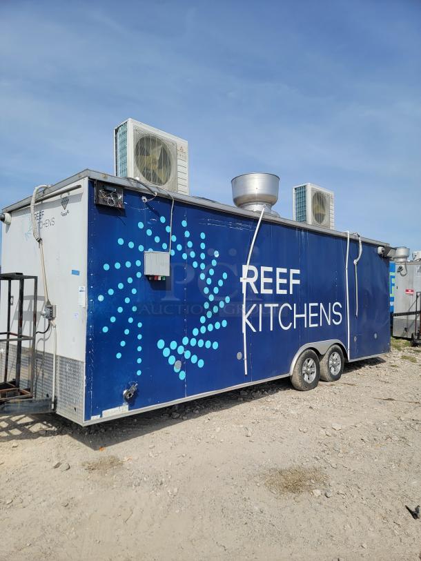 Mobile kitchen trailer labeled "REEF KITCHENS," featuring two wheels, rooftop AC units, and exhaust vent. Mild wear visible.