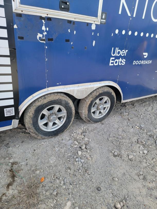 Blue food truck side view with logos, twin wheels, and wear signs. Brands: Uber Eats, DoorDash. Used condition.
