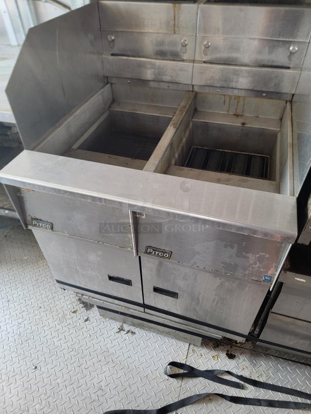 Pitco commercial fryer with dual vats, stainless steel finish, visible grease and wear, branded front panel, industrial kitchen use.