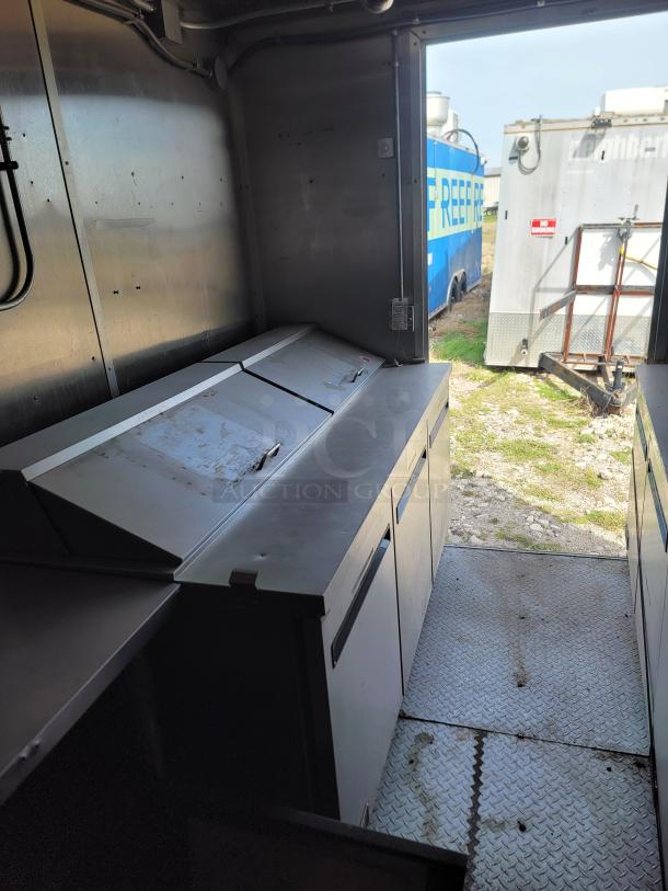 Industrial metal workstation with closed compartments inside a trailer. Signs of wear. Suitable for mobile operations.