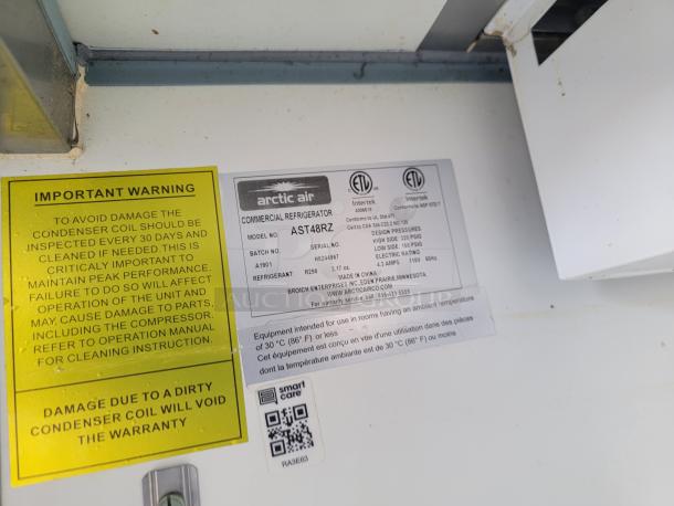 Arctic Air commercial refrigerator, model AST48RZ, warning label about condenser coil maintenance, ETL certified.