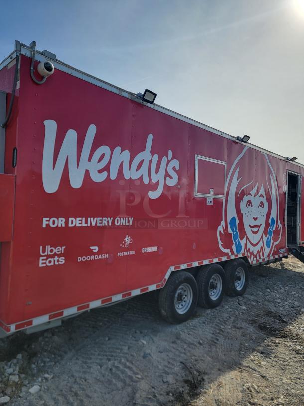 Red Wendy's delivery-only food truck with logos for Uber Eats, DoorDash, Postmates, Grubhub. Tri-axle design on rough terrain.