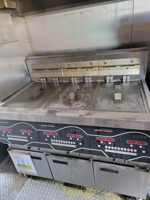Henny Penny commercial fryer with digital controls, stainless steel, multiple frying compartments, slightly worn condition.