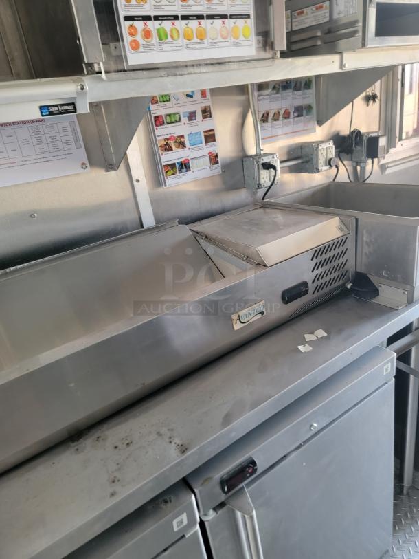Avantco stainless steel sandwich prep table, features a refrigerated cabinet and top pan storage, in used condition with visible grime.