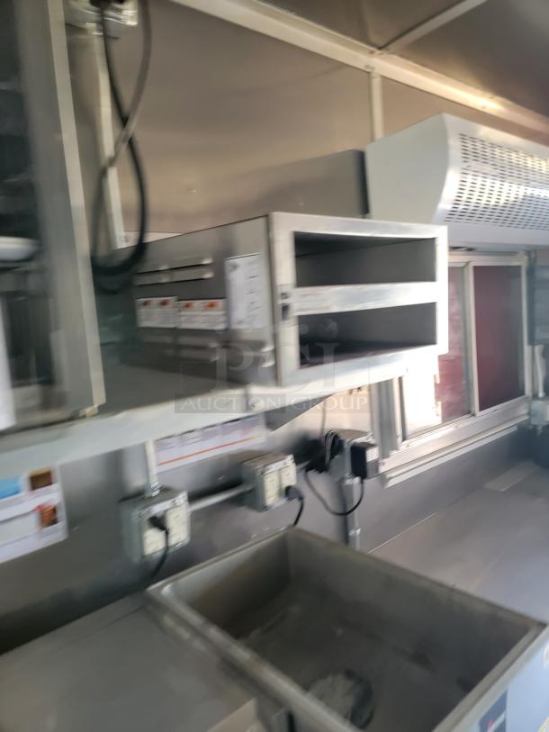 Commercial kitchen interior with metal shelving, a ventilation system, storage compartments, and electric outlets. Appears well-maintained.