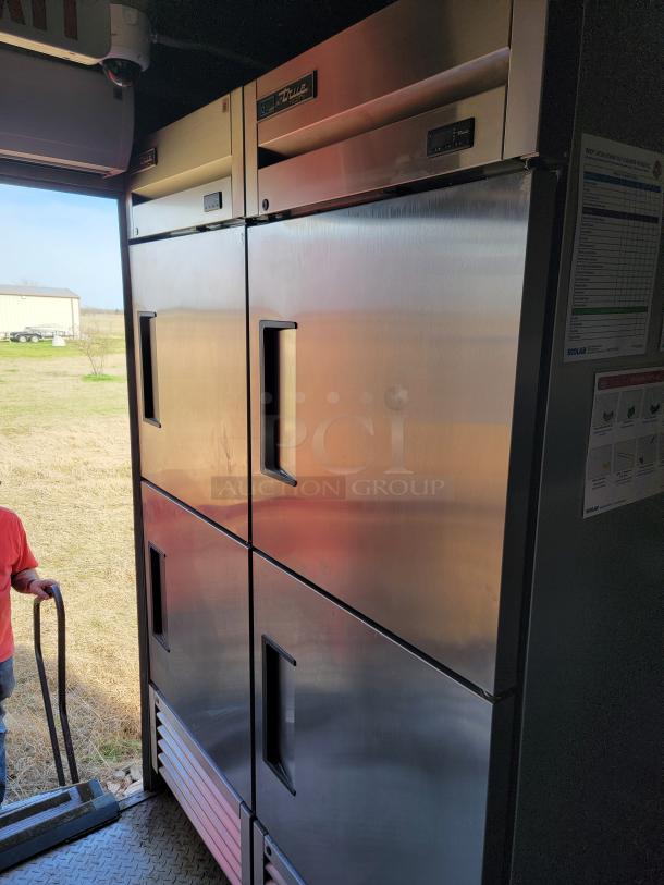 True double glass door commercial refrigerator in stainless steel. Features digital temperature display. Slight wear visible.