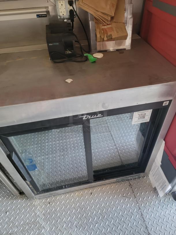 Stainless steel True sliding glass door refrigerator, diamond plate flooring. Detailing as visible. Good condition.