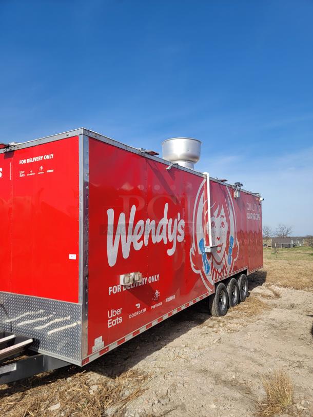 Red Wendy's food trailer with delivery service logos, featuring a large ventilation unit on top. Signs for Uber Eats, DoorDash.