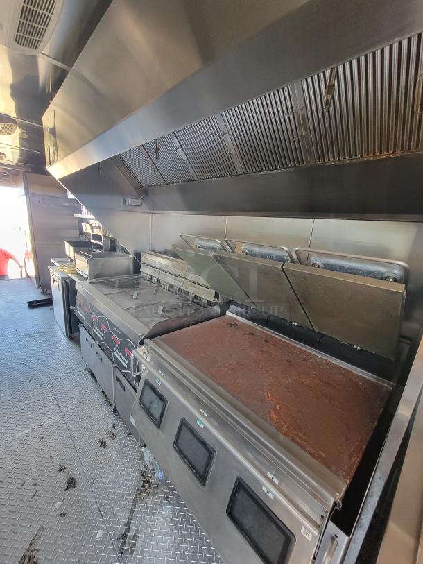 Commercial kitchen equipment with grills and exhaust hoods in a professional setup, showcasing stainless steel surfaces.