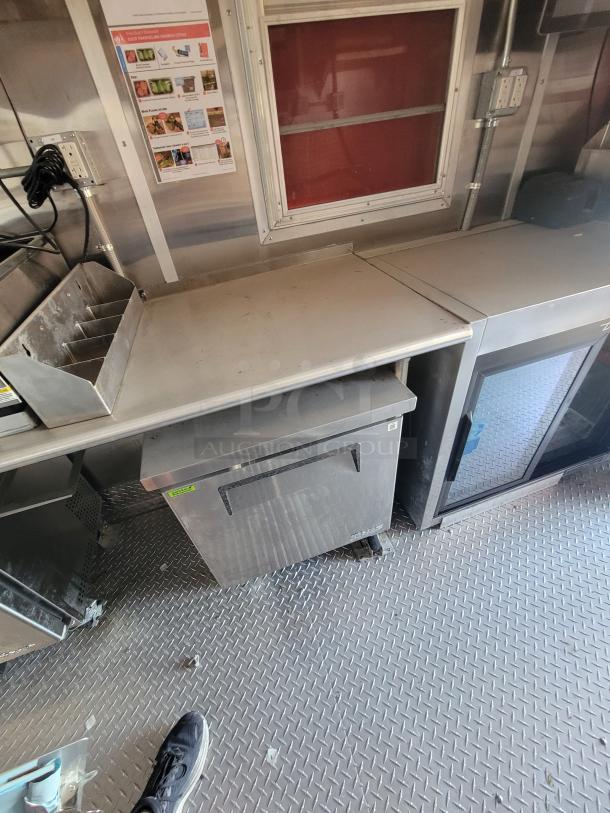 Stainless steel food truck counter with storage units, prep area, and power outlets. Light wear, ideal for commercial use.