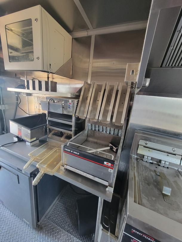 Commercial kitchen equipment featuring a Crisp N’ Hold warmer, Henny Penny fryer, and storage units, in good condition.