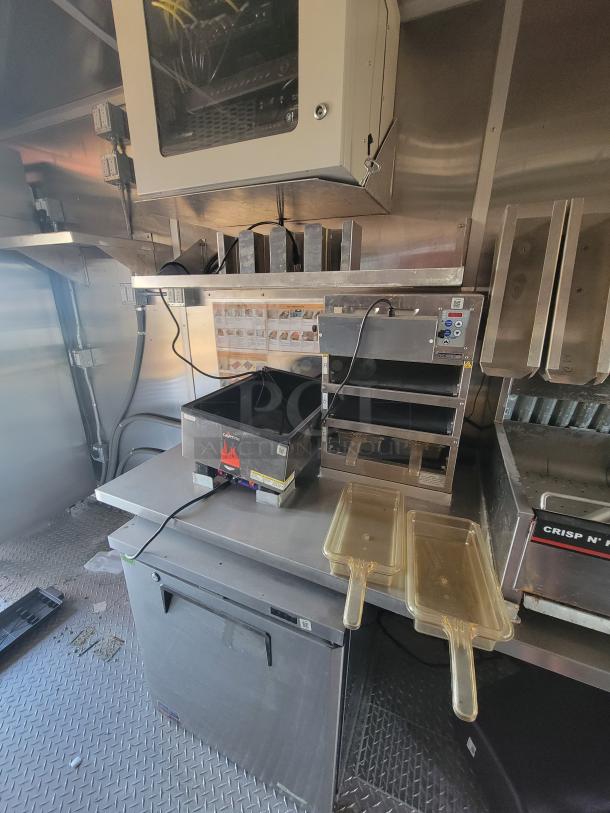 Commercial kitchen interior with stainless steel equipment, including a fryer and Crisp N' Hold unit. Well-maintained condition.
