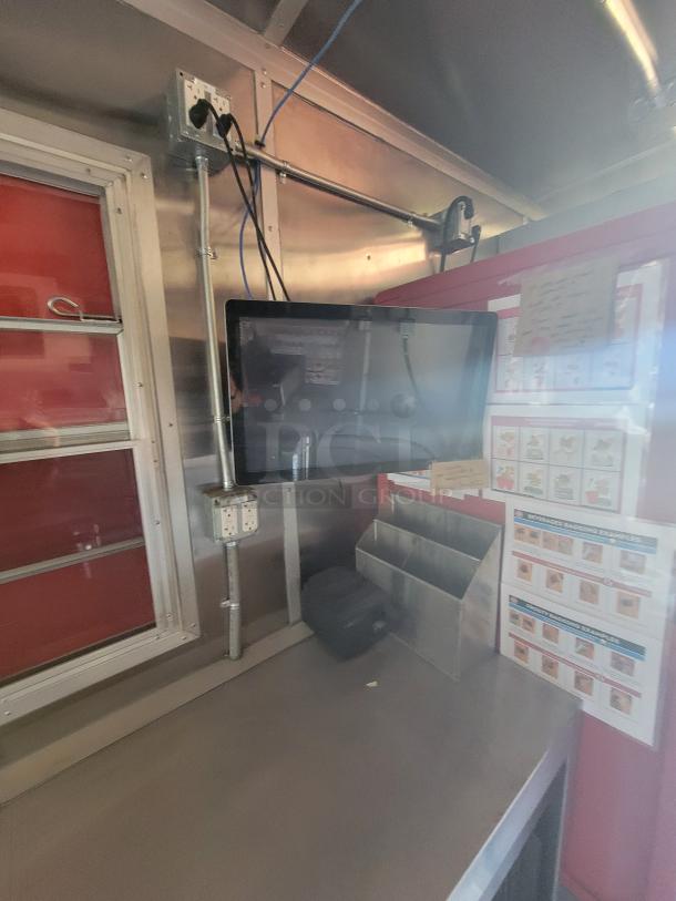 Industrial kitchen counter with a mounted touchscreen, cables, power outlets, and a metal organizer. Clean and well-maintained.