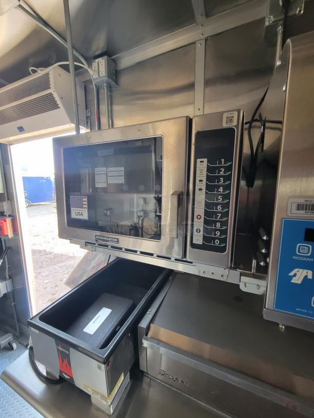 Commercial stainless steel microwave, brand Menumaster, with digital keypad and USA label, used condition, in a kitchen setting.