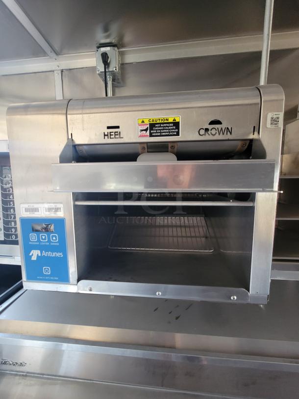 Antunes commercial toaster with stainless steel finish. Features "HEEL" and "CROWN" labeling. Includes caution sticker and QR code.