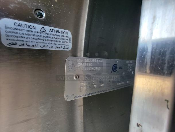 Metallic commercial kitchen appliance with caution label and Garland Commercial Ranges Ltd. serial number plate. Model XPE36AC.