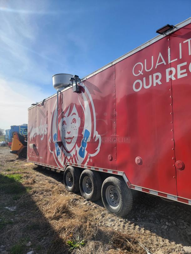 Red Wendy's branded food truck with triple axle wheels, featuring company logo and slogan "Quality is Our Recipe" on the side.