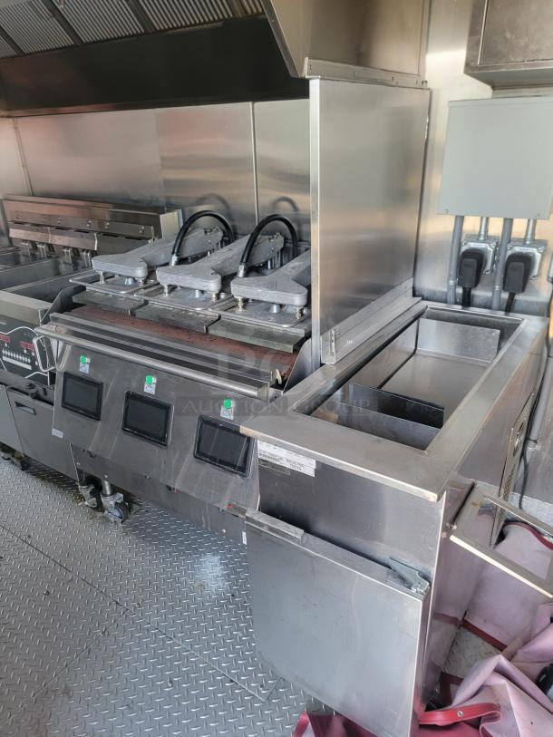 Commercial stainless steel kitchen equipment with multiple sandwich presses, digital controls, and vent hood. Appears in good condition.