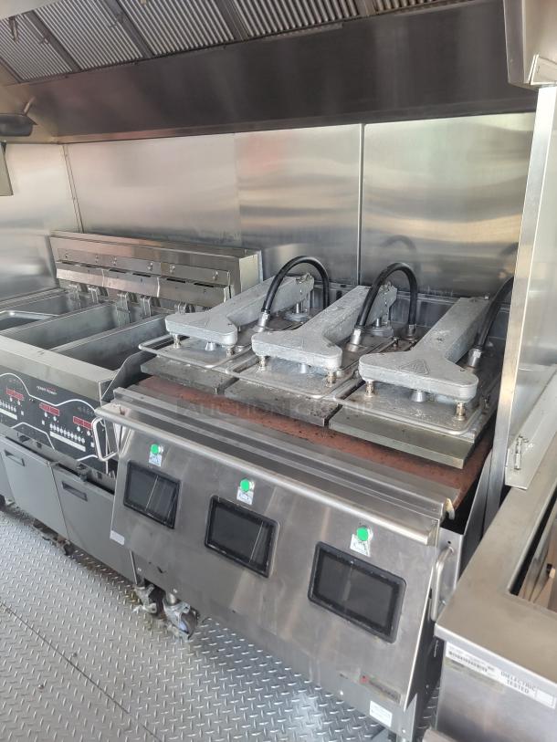 Commercial kitchen equipment with multiple deep fryers and grills in stainless steel, featuring digital controls. Excellent condition.