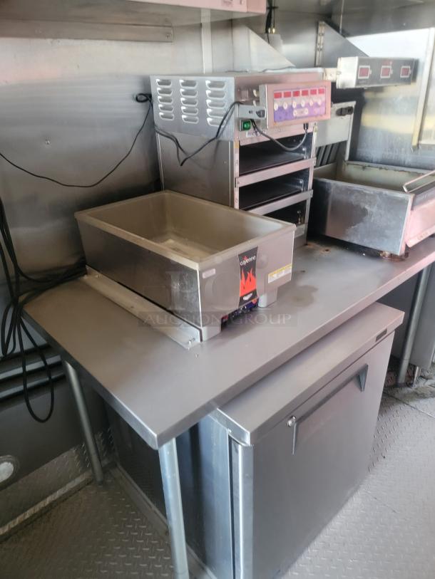 Commercial kitchen equipment with fryer and oven units on stainless steel countertop, featuring Coyote brand decal, good condition.